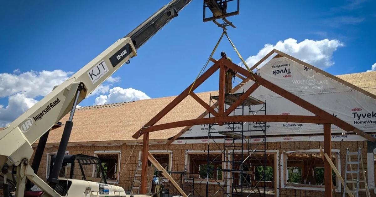 large forklift installing timber accent frame to front entrance of a home on a construction site